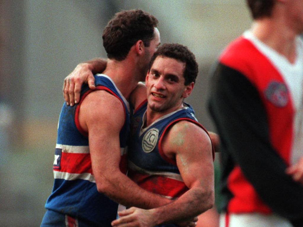Nigel Kellett and [PLAYERCARD]Tony Liberatore[/PLAYERCARD] embrace during an AFL game in the 1990s. Kellett, now 54, can hardly remember his Brownlow Medal-winning former teammate due to repeated head knocks across his career.