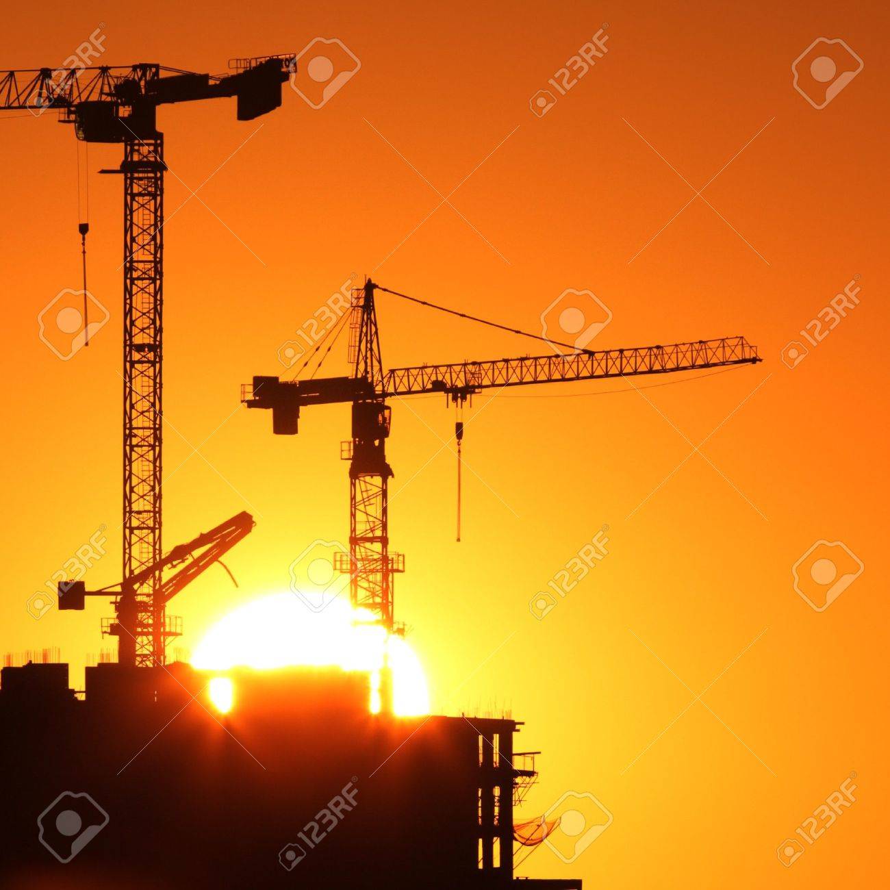 7411859-Industrial-construction-cranes-and-building-silhouettes-over-sun-at-sunrise--Stock-Photo.jpg