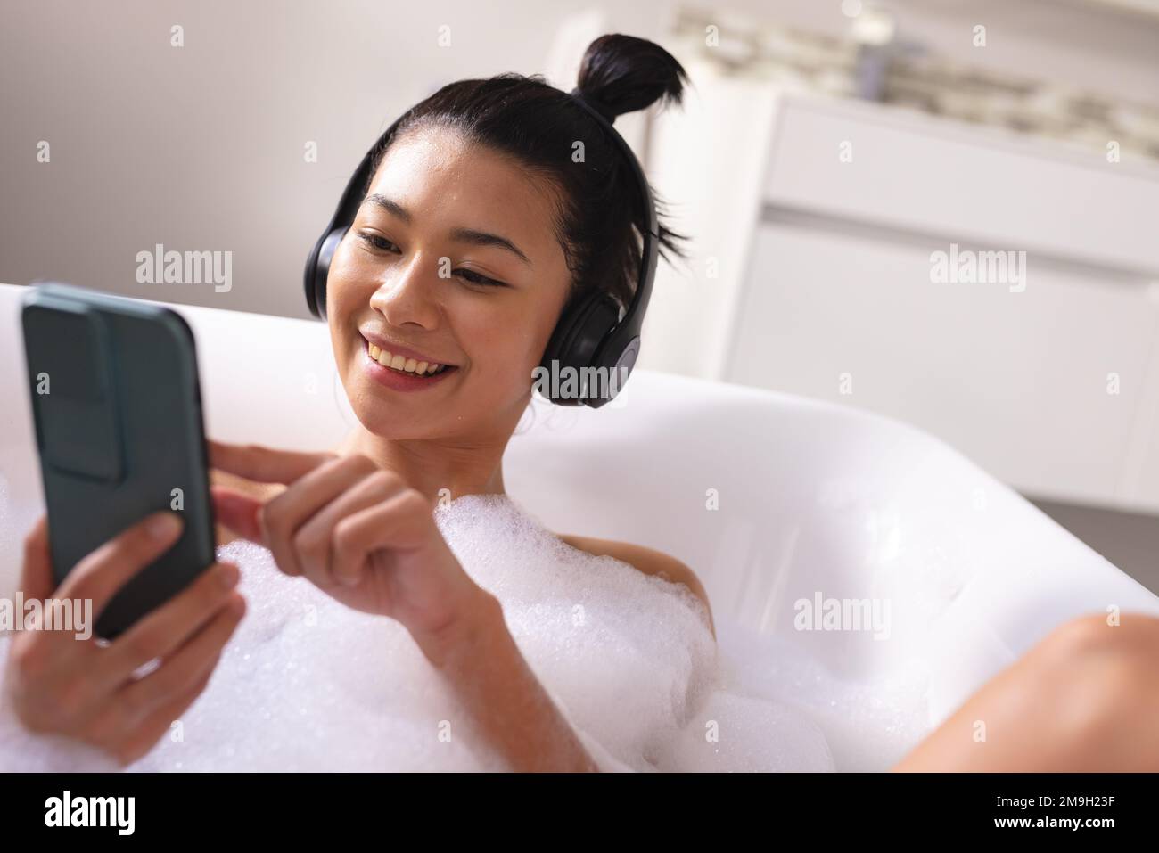 image-of-biracial-woman-relaxing-with-headphones-and-smartphone-in-bathtub-in-bubble-bath-2M9H23F.jpg