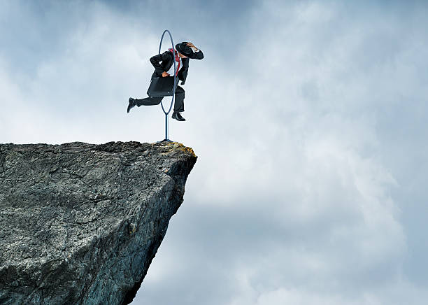 businessman-jumping-through-hoops-at-edge-of-cliff.jpg