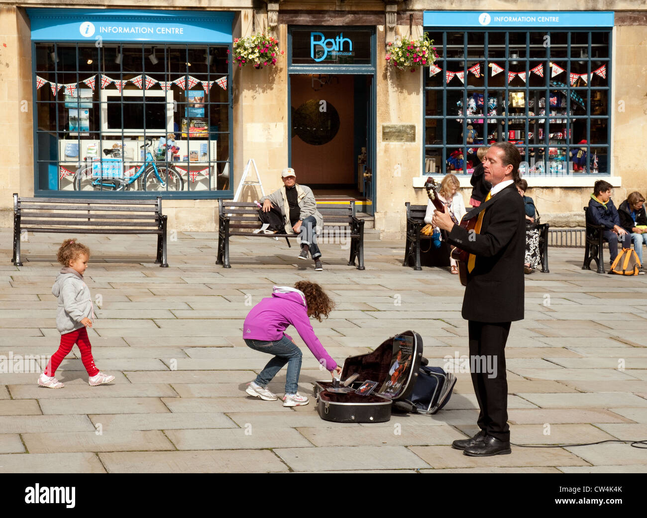 a-child-giving-money-to-a-busker-playing-in-the-abbey-churchyard-bath-CW4K4K.jpg