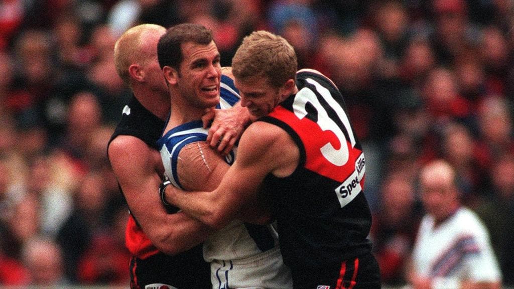 Dean Wallis and Dustin Fletcher gang tackle Wayne Carey during a match in 1999.