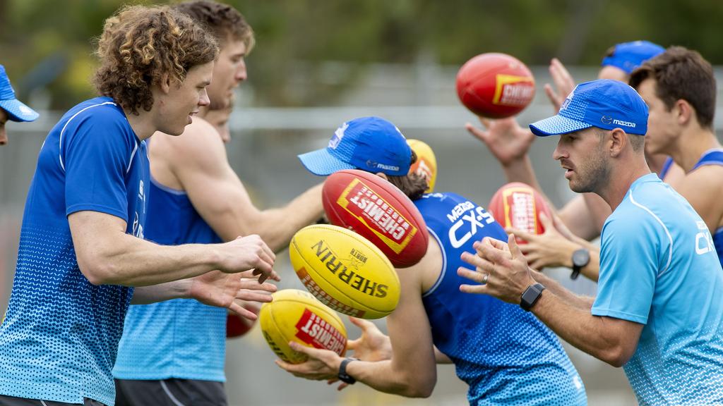 North Melbourne assistant coach Brendan Whitecross handballs with Ben Brown.