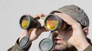 man-binoculars-sun-watch-a-man-watching-the-surroundings-through-a-pair-of-military-binoculars-the-orange-glass-lenses-reflect-buildings-trees-and-the-sunny-sky_eyqlhqy8__S0000.jpg