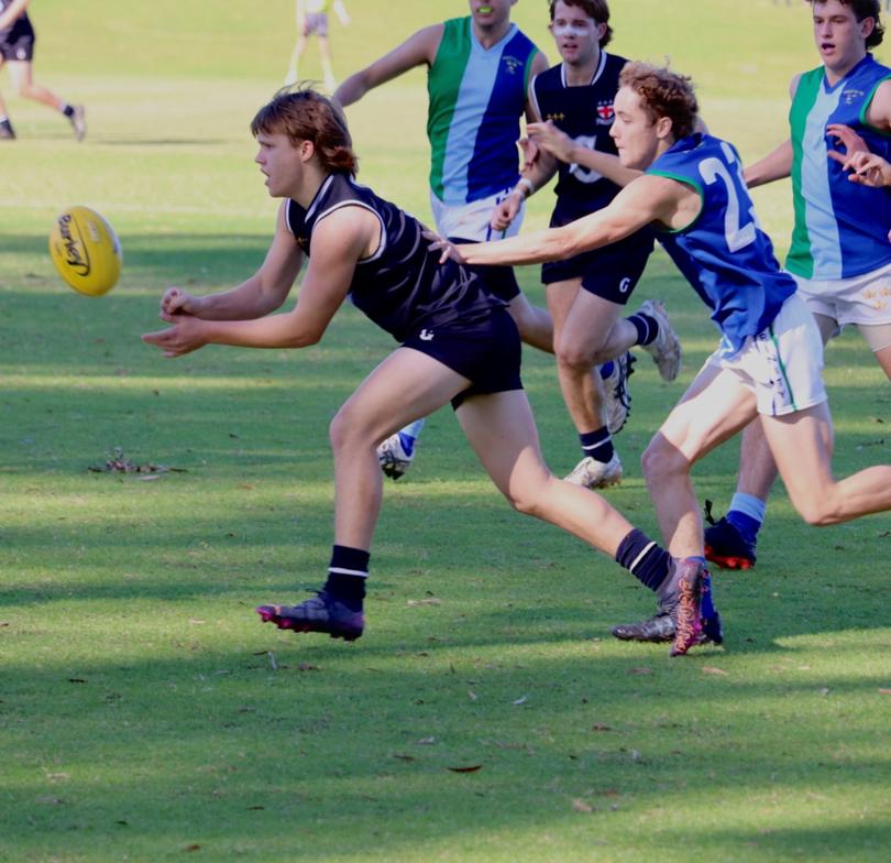 Guildford captain Luke Kelly gets a handball away during his school's breakthrough win over Trinity.