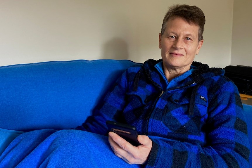 Woman in blue checked jacket sits on a blue couch