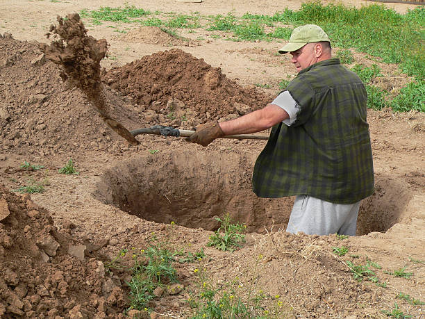 rugged-man-digging-deep-hole-with-shovel-picture-id92054054