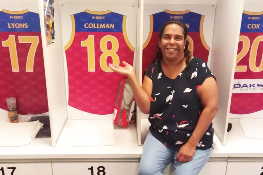 Auntie Bernice Broome sits in front of the locker with the Brisbane Lions guernsey of her nephew Keidean Coleman.