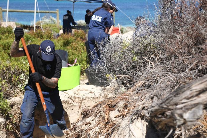 police with shovels search dunes with ocean in the background