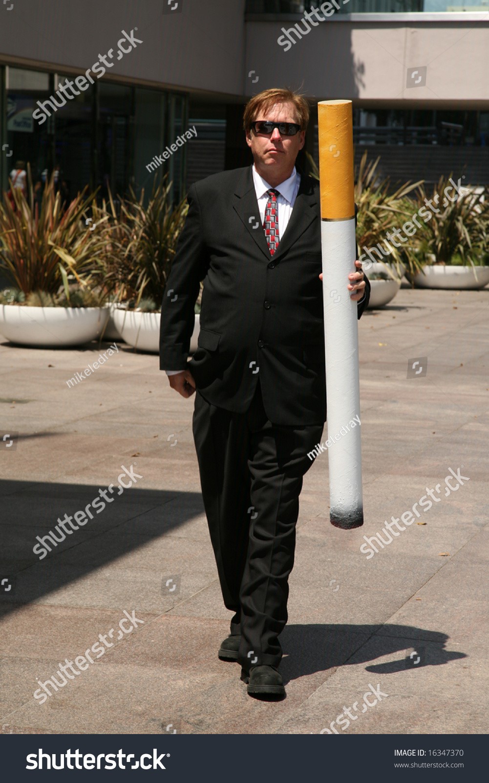 stock-photo-anti-smoking-concepts-a-business-man-in-a-suit-holds-a-giant-cigarette-with-a-book-of-matches-16347370.jpg